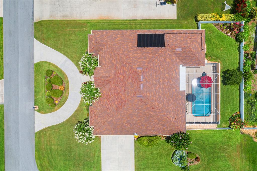 An aerial view of a house with a shingled roof, pool enclosure, and landscaped yard — 328 HAMILTON SHORES DRIVE NE, WINTER HAVEN, FL