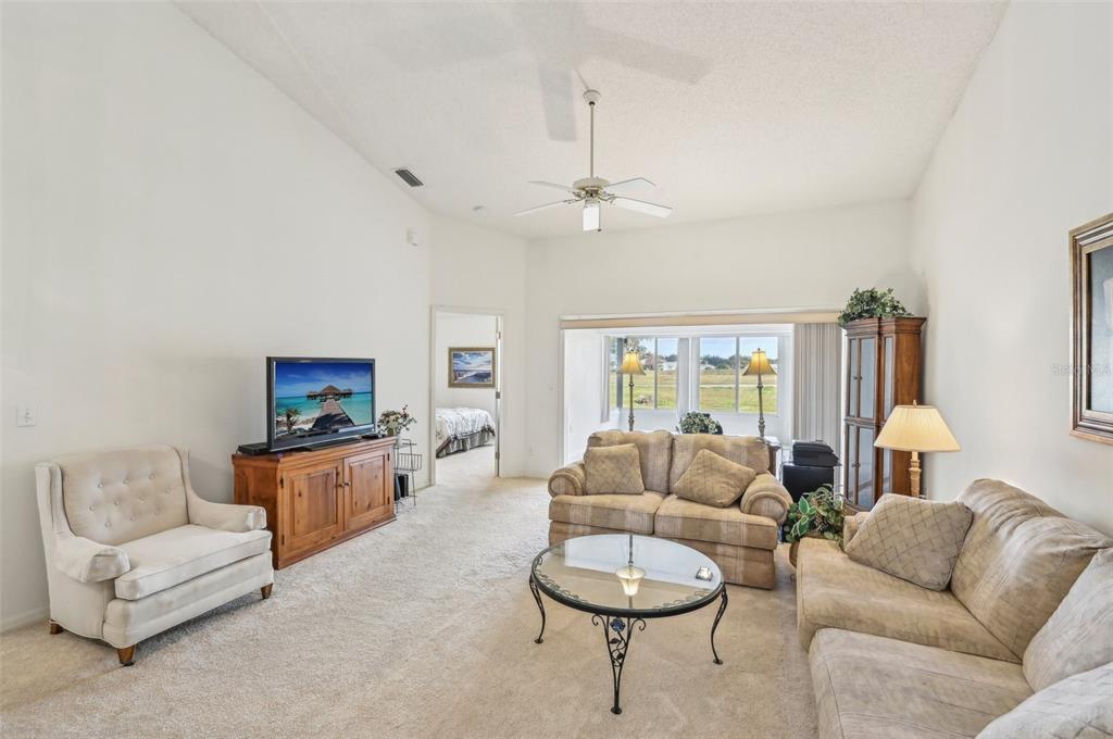 A living room with beige carpet, a vaulted ceiling, a sofa, and a glass coffee table — 2315 NEW ORCHARD COURT, SUN CITY CENTER, FL