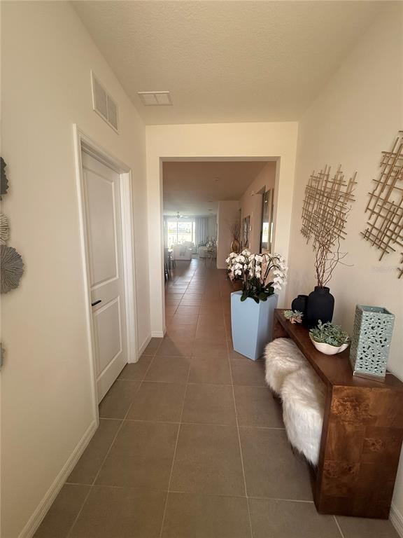 A hallway with tile flooring leads to an open living area featuring a console table — 988 VINEYARD RIDGE ROAD, MINNEOLA, FL