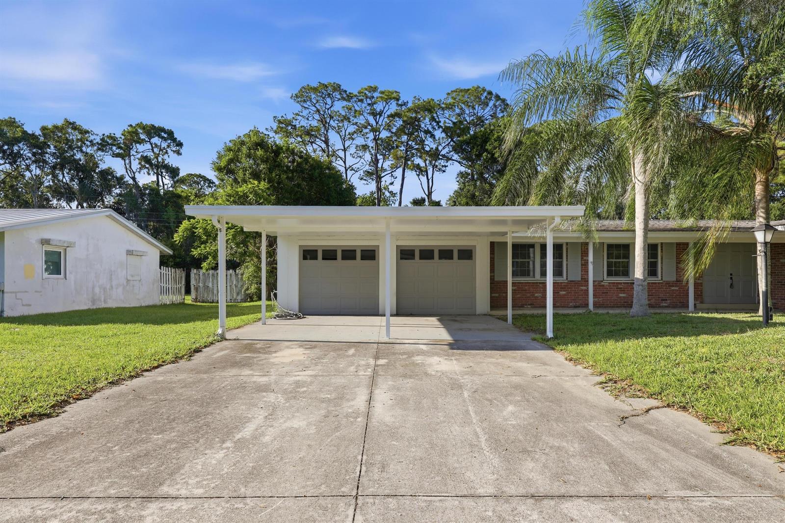 A house exterior features a concrete driveway leading to a two-car carport and garage — 2726 6th Place, Vero Beach FL 32968, VERO BEACH, FL