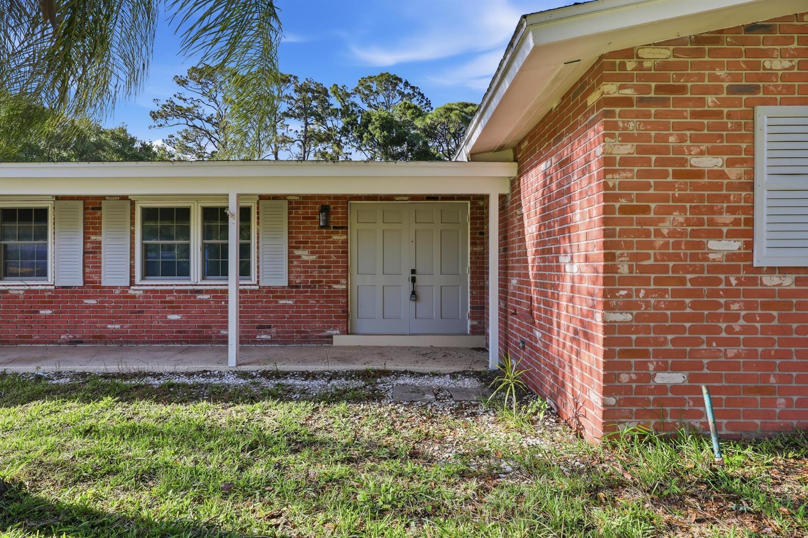 A red brick house exterior features a covered porch and a light gray double door — 2726 6th Place, Vero Beach FL 32968, VERO BEACH, FL