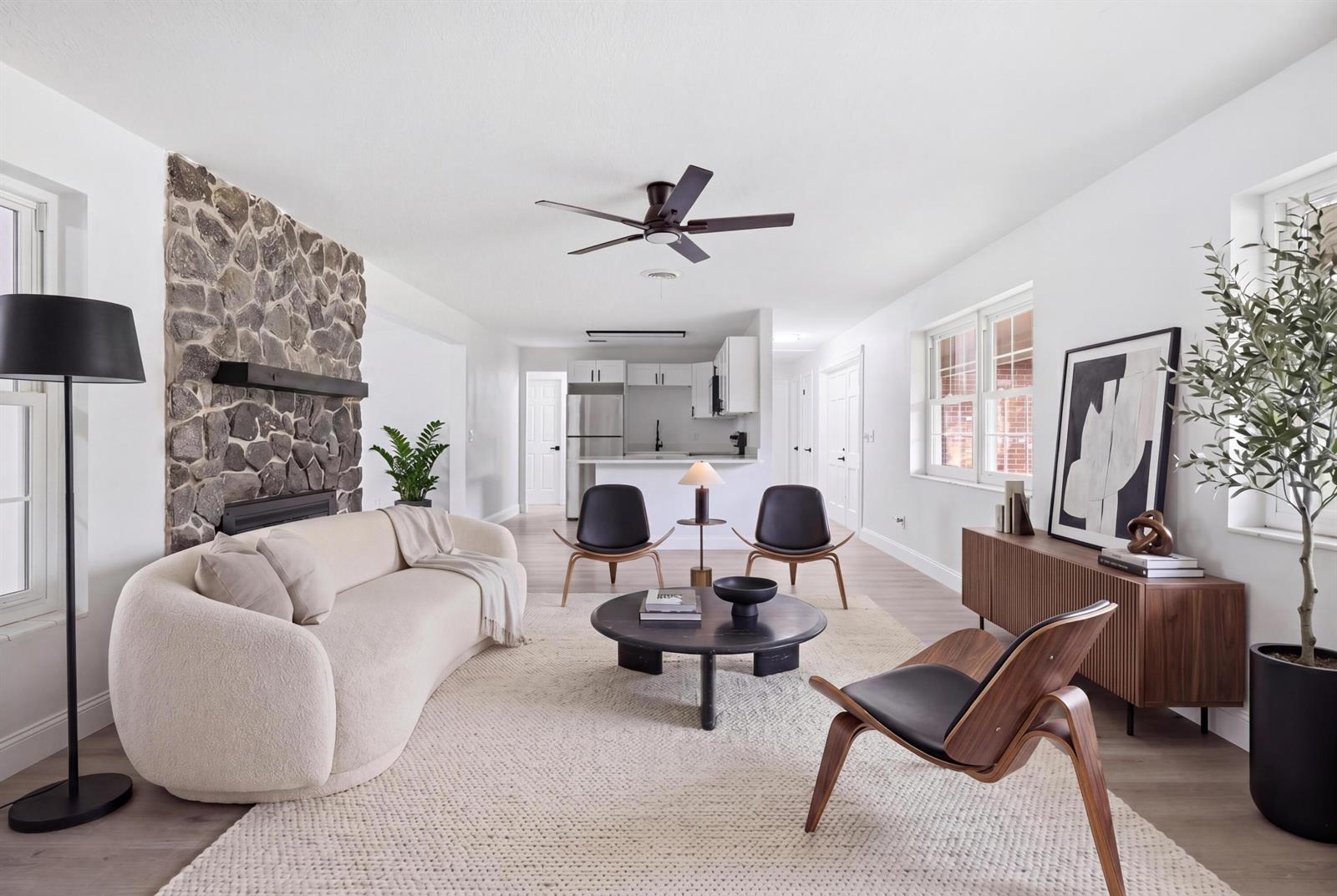 A living room features a stone fireplace, a curved cream sofa, and mid-century modern chairs — 2726 6th Place, Vero Beach FL 32968, VERO BEACH, FL