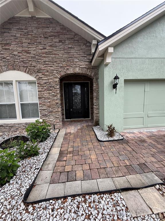 The home exterior features a stone facade, a paved walkway, and a light green garage — 16321 SAINT AUGUSTINE STREET, CLERMONT, FL