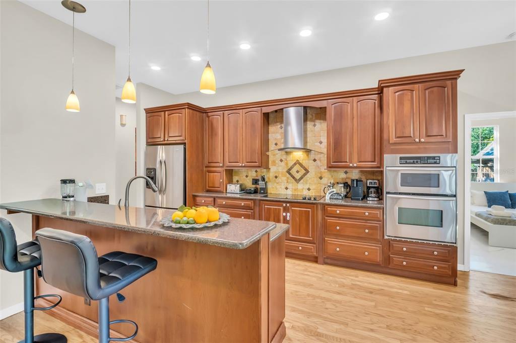 A kitchen with wood cabinets, stainless steel appliances, and a granite-topped island with bar stools — 2270 BARBARA DRIVE, CLEARWATER, FL