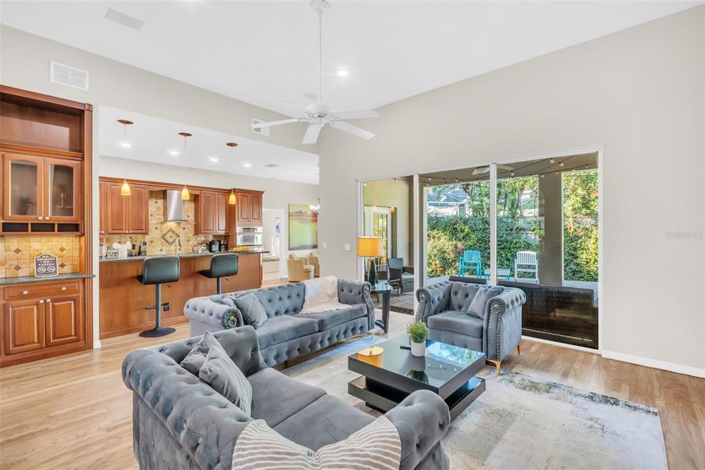 A living room with grey tufted furniture opens to a kitchen with wood cabinetry — 2270 BARBARA DRIVE, CLEARWATER, FL