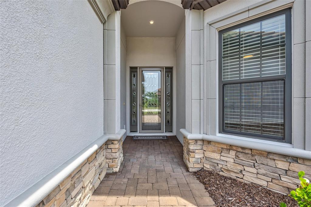 A paved walkway leads to a front entrance with a glass door and stone accents — 5880 SEMOLINO STREET, NOKOMIS, FL