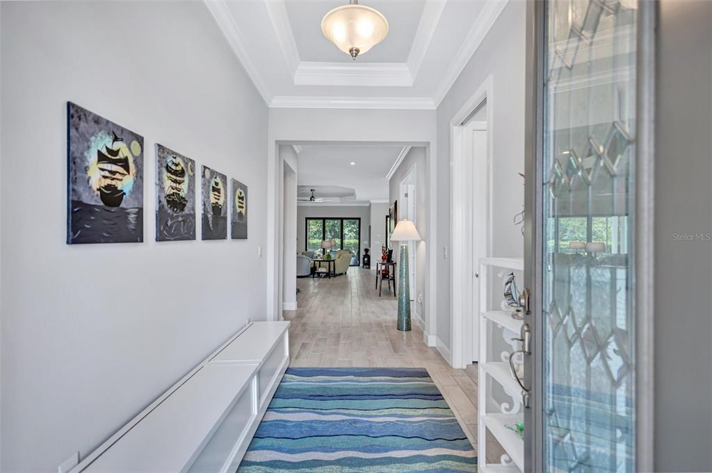 A bright entryway features a blue striped rug, white built-in bench, and nautical wall art — 5880 SEMOLINO STREET, NOKOMIS, FL