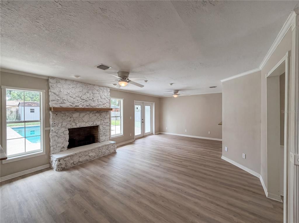 A living room features light wood-look flooring, a white stone fireplace, and glass patio doors — 1770 NE 37TH STREET, OCALA, FL