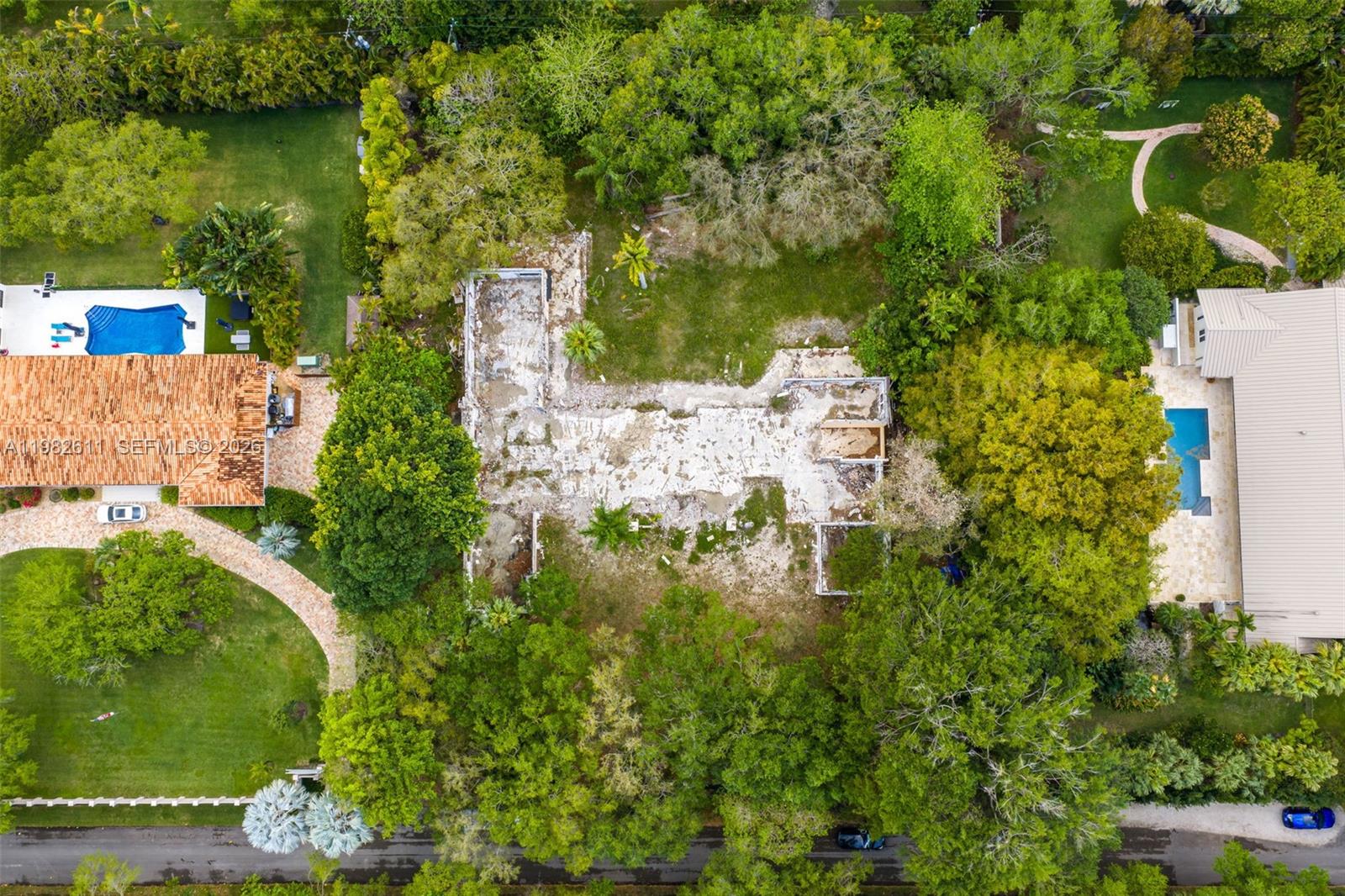 An aerial view shows a residential lot with a demolished building foundation surrounded by trees — 10550 Old Cutler Rd, Coral Gables FL 33156, CORAL GABLES, FL