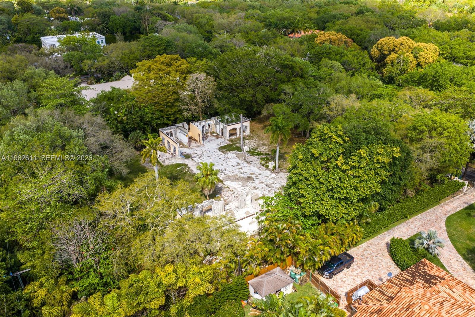 An aerial view shows a partially demolished house surrounded by dense trees and vegetation — 10550 Old Cutler Rd, Coral Gables FL 33156, CORAL GABLES, FL