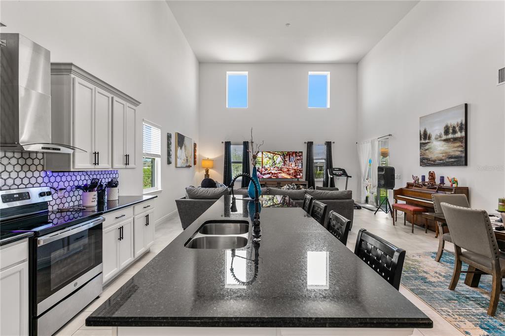 A modern open-concept kitchen with a large island overlooks a spacious living area — 5637 BEGGS ROAD, ST CLOUD, FL