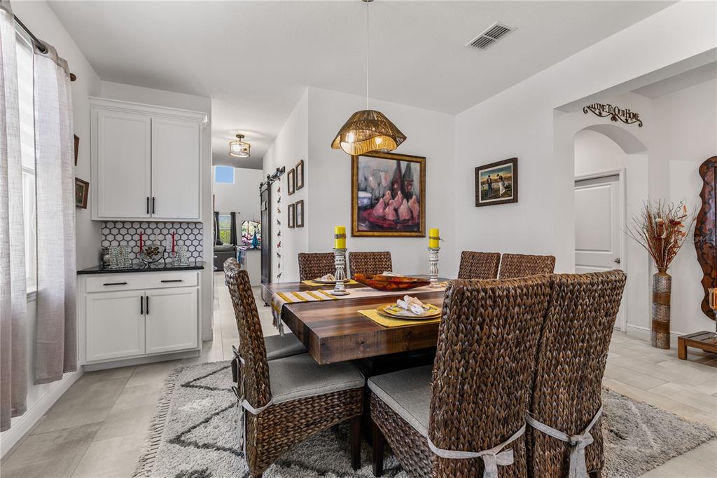 A dining room features a wooden table, woven chairs, white cabinets, and a patterned rug — 5637 BEGGS ROAD, ST CLOUD, FL