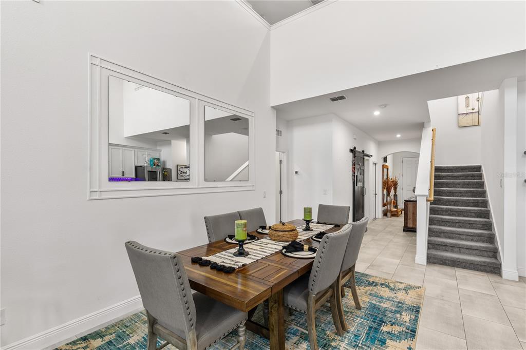 A dining room features a wooden table, gray upholstered chairs, and a staircase — 5637 BEGGS ROAD, ST CLOUD, FL