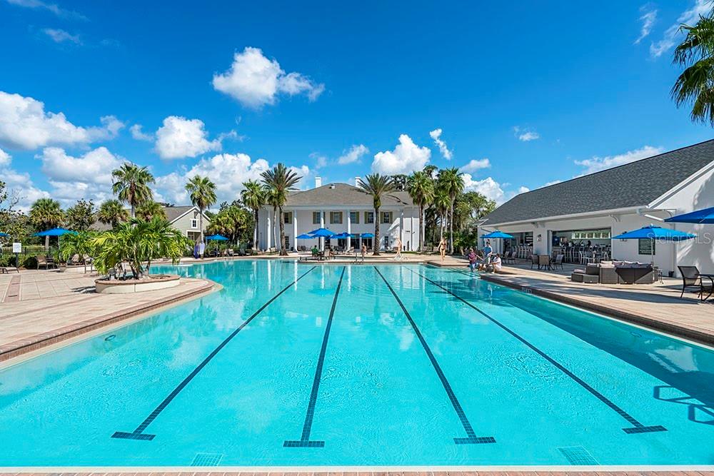 A large outdoor swimming pool with lap lanes sits in front of a white clubhouse — 19844 ENGLISH WALNUT PLACE, BROOKSVILLE, FL