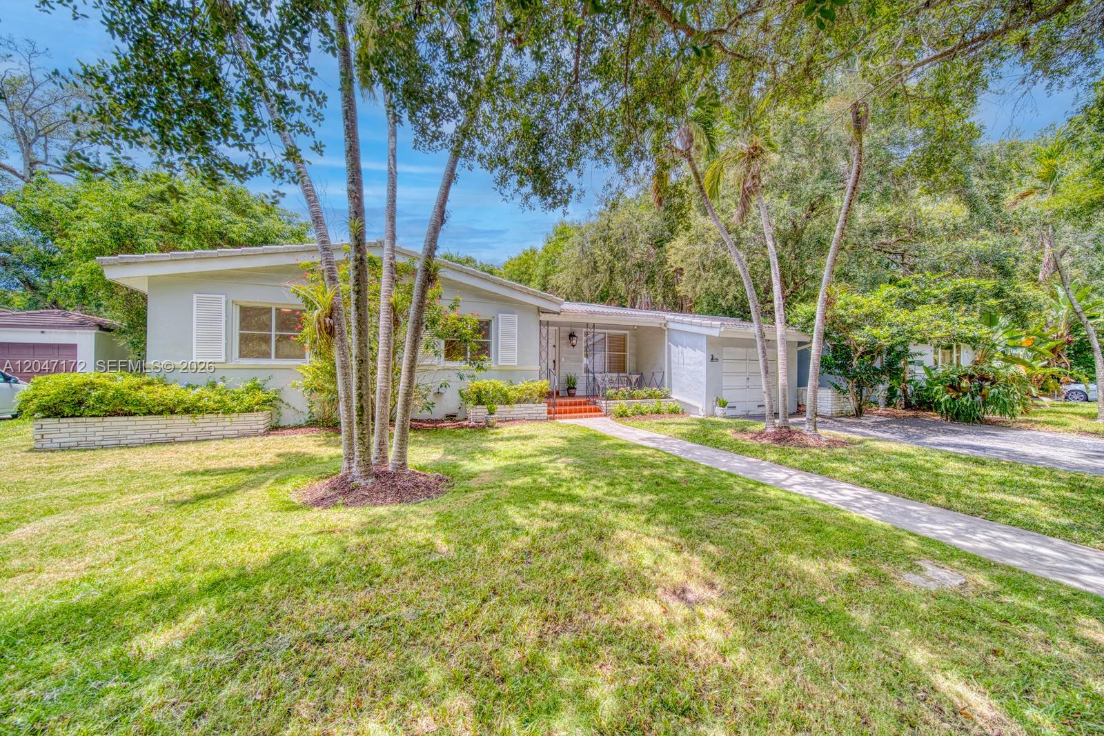 A single-story house with a light-colored exterior, a front lawn, and mature trees — 1116 Almeria Ave, Coral Gables FL 33134, CORAL GABLES, FL
