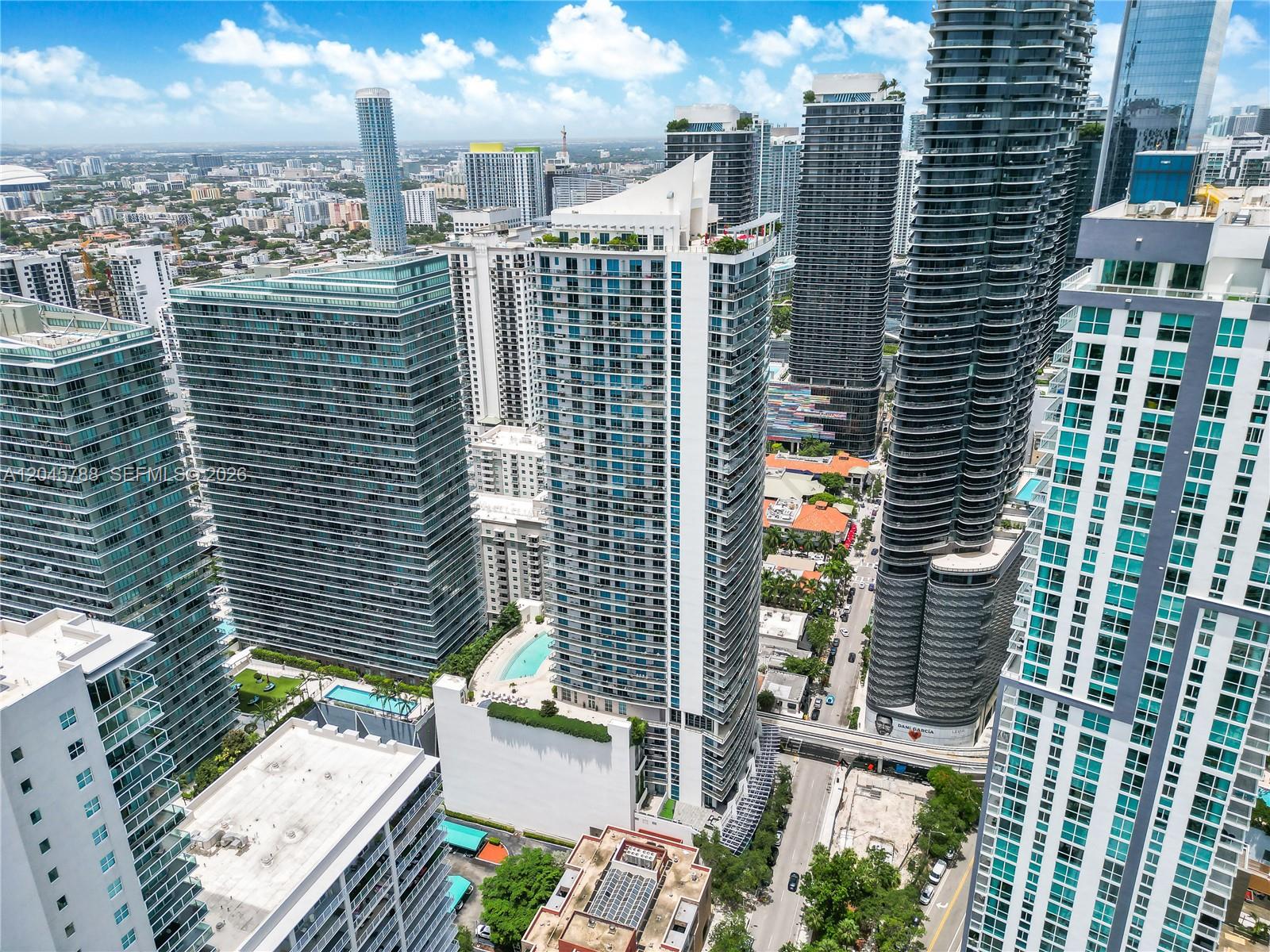 An aerial view shows multiple modern high-rise residential buildings in a dense urban city — 1100 S Miami Ave # 1607, Miami FL 33130, MIAMI, FL