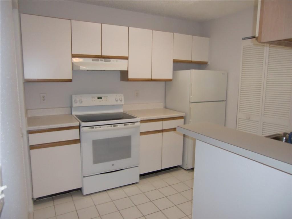 A kitchen features white cabinets, white appliances, a tiled floor, and a breakfast bar — 4045 Mcnab Road # G, Pompano Beach FL 33069, POMPANO BEACH, FL