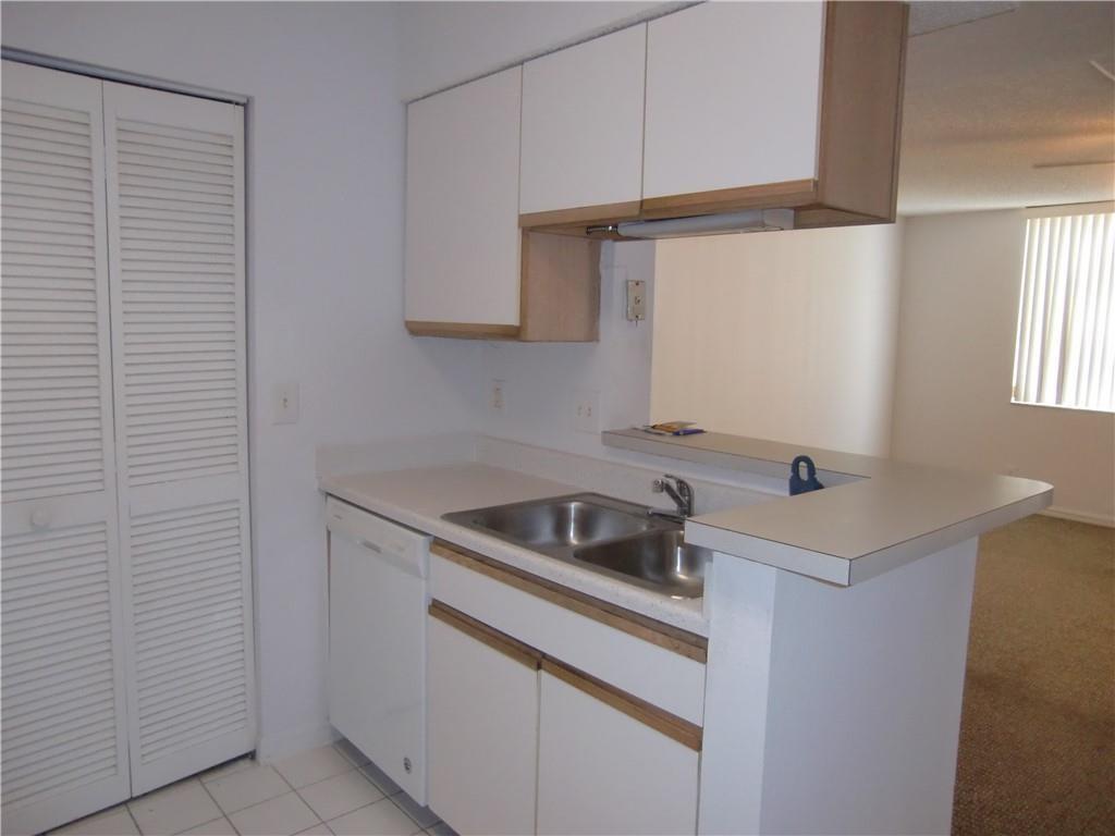 A kitchen with white cabinets, a double sink, and a dishwasher, opening to a living area — 4045 Mcnab Road # G, Pompano Beach FL 33069, POMPANO BEACH, FL