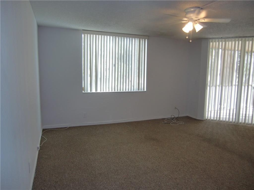An empty room features beige carpeting, white walls, vertical blinds, and a ceiling fan — 4045 Mcnab Road # G, Pompano Beach FL 33069, POMPANO BEACH, FL