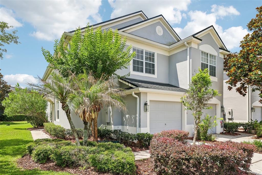 A two-story gray townhouse with a two-car garage and landscaped front yard — 15054 BELLINKOFF LANE, ORLANDO, FL