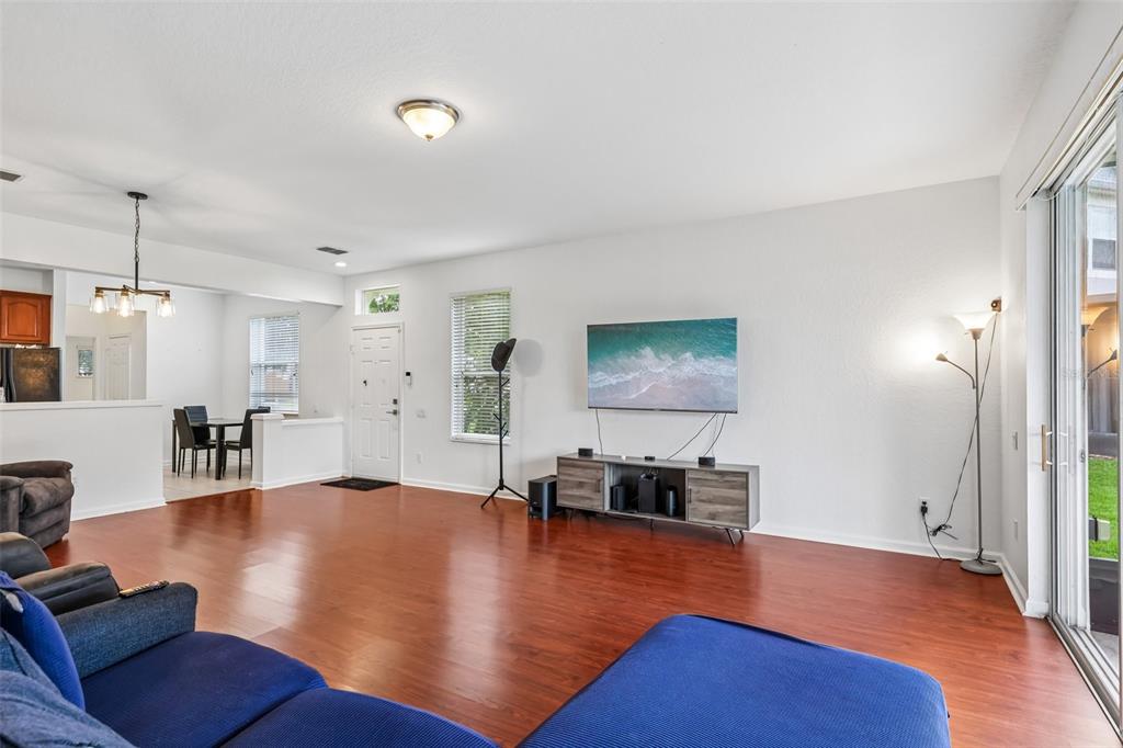 A living room features hardwood floors, a wall-mounted television, and a sliding glass door — 15054 BELLINKOFF LANE, ORLANDO, FL