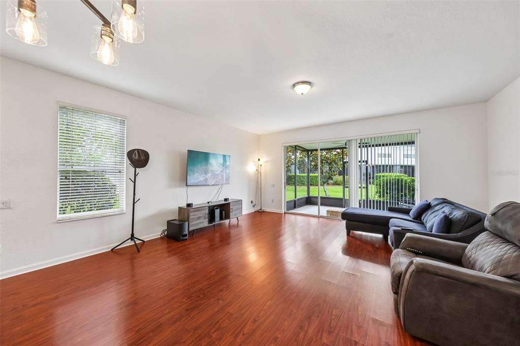 A living room features hardwood floors, a wall-mounted television, and a sliding door to a patio — 15054 BELLINKOFF LANE, ORLANDO, FL