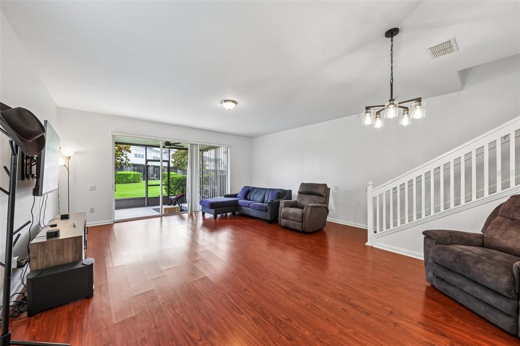 A living room with wood-look flooring, a staircase, and sliding glass doors to a patio — 15054 BELLINKOFF LANE, ORLANDO, FL