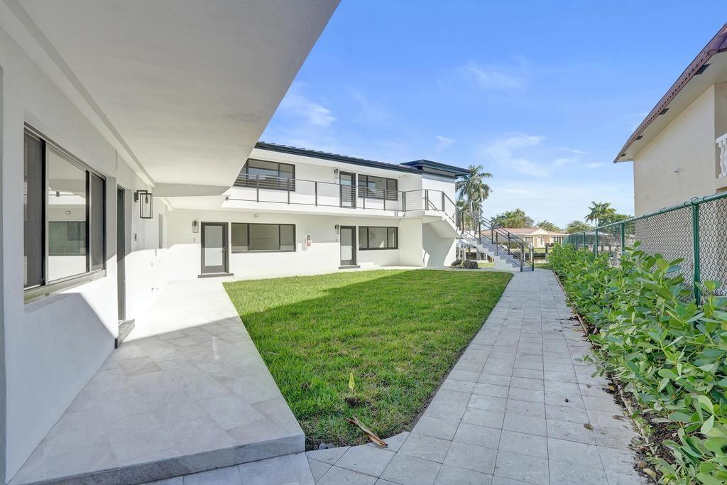 A white two-story building with a grassy courtyard, paved walkways, and an exterior staircase — 840 SE 22nd Avenue, Pompano Beach FL 33062, POMPANO BEACH, FL