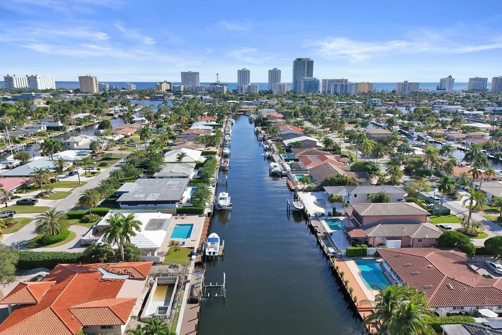 An aerial view shows a canal lined with houses, swimming pools, and boats near a city — 840 SE 22nd Avenue, Pompano Beach FL 33062, POMPANO BEACH, FL