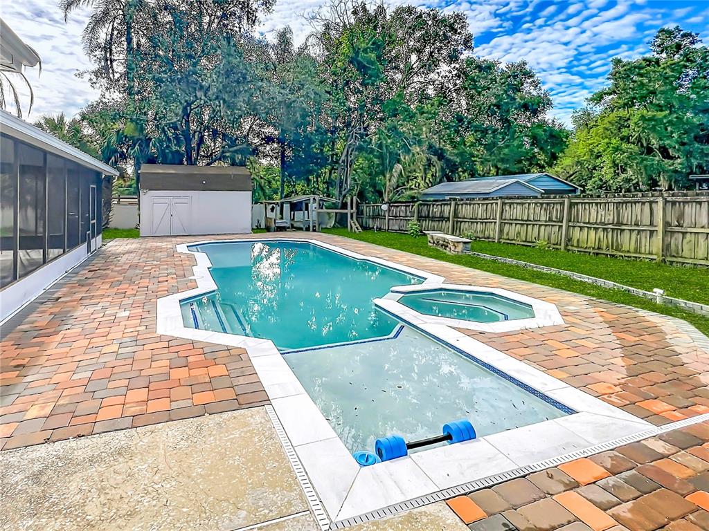 A backyard features an irregularly shaped swimming pool with an attached spa and paver patio — 52 CLARK STREET, OVIEDO, FL