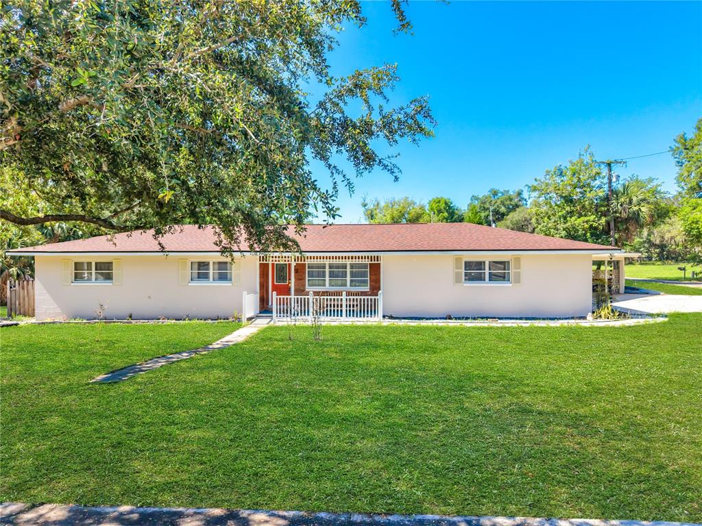 A single-story house with a light-colored exterior, a red roof, and a front lawn — 52 CLARK STREET, OVIEDO, FL
