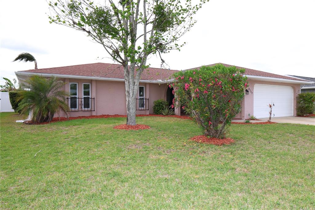 A single-story house with a pink exterior, a white garage door, and a front lawn — 9737 SAN VINCENTE WAY, PORT RICHEY, FL