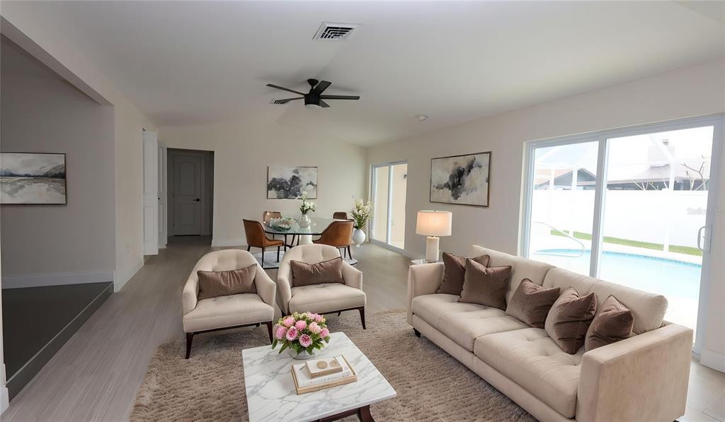 A living room and dining area with light flooring, neutral furniture, and a pool view — 9737 SAN VINCENTE WAY, PORT RICHEY, FL