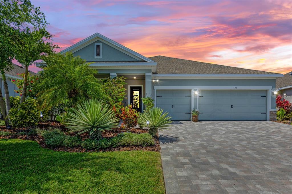 A single-story house with a blue exterior, a two-car garage, and a paver driveway — 5526 GAVELLA COVE, PALMETTO, FL
