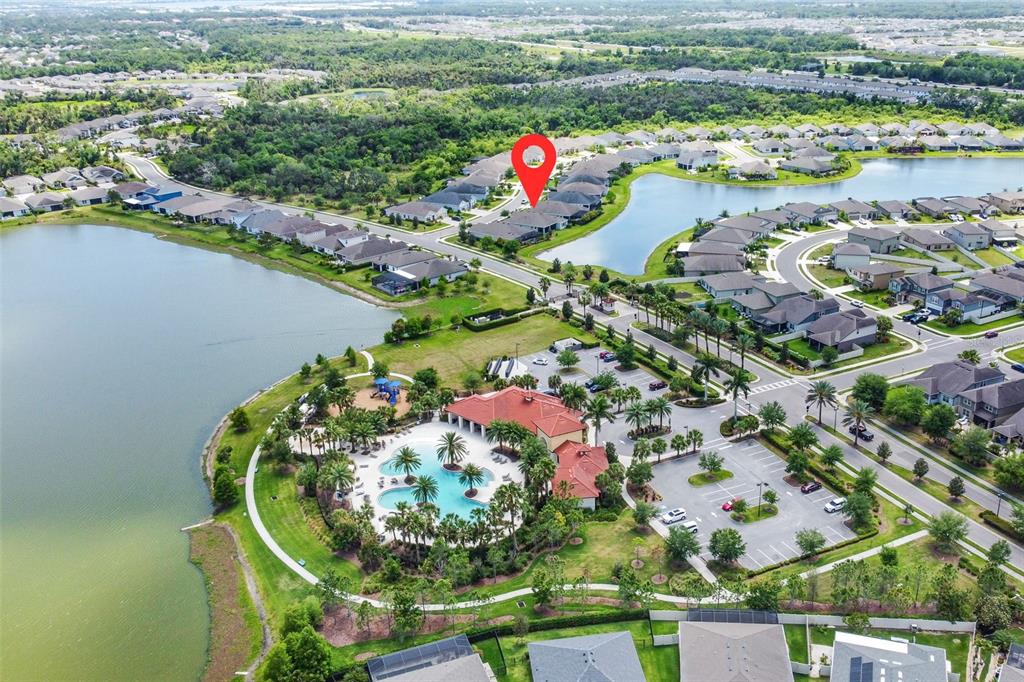 This aerial view shows a residential community with a clubhouse, swimming pool, and lake — 5526 GAVELLA COVE, PALMETTO, FL