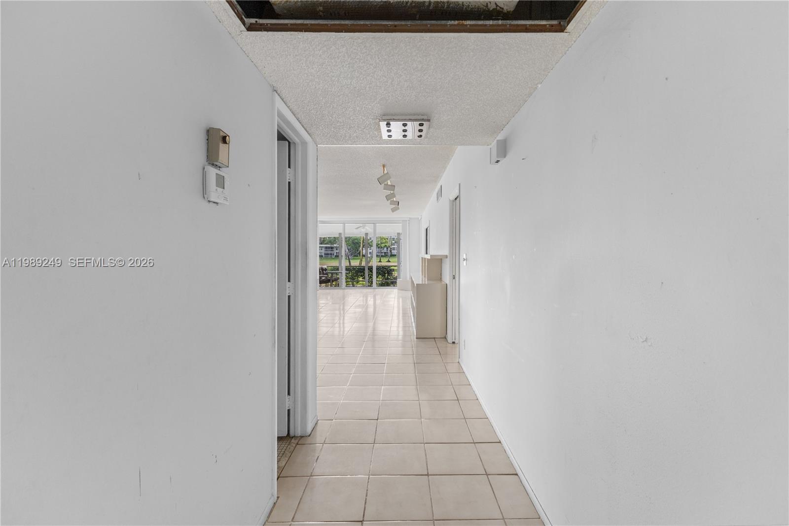 A tiled hallway leads toward a bright living area with floor-to-ceiling windows — 806 Cypress Grove Ln # 111, Pompano Beach FL 33069, POMPANO BEACH, FL