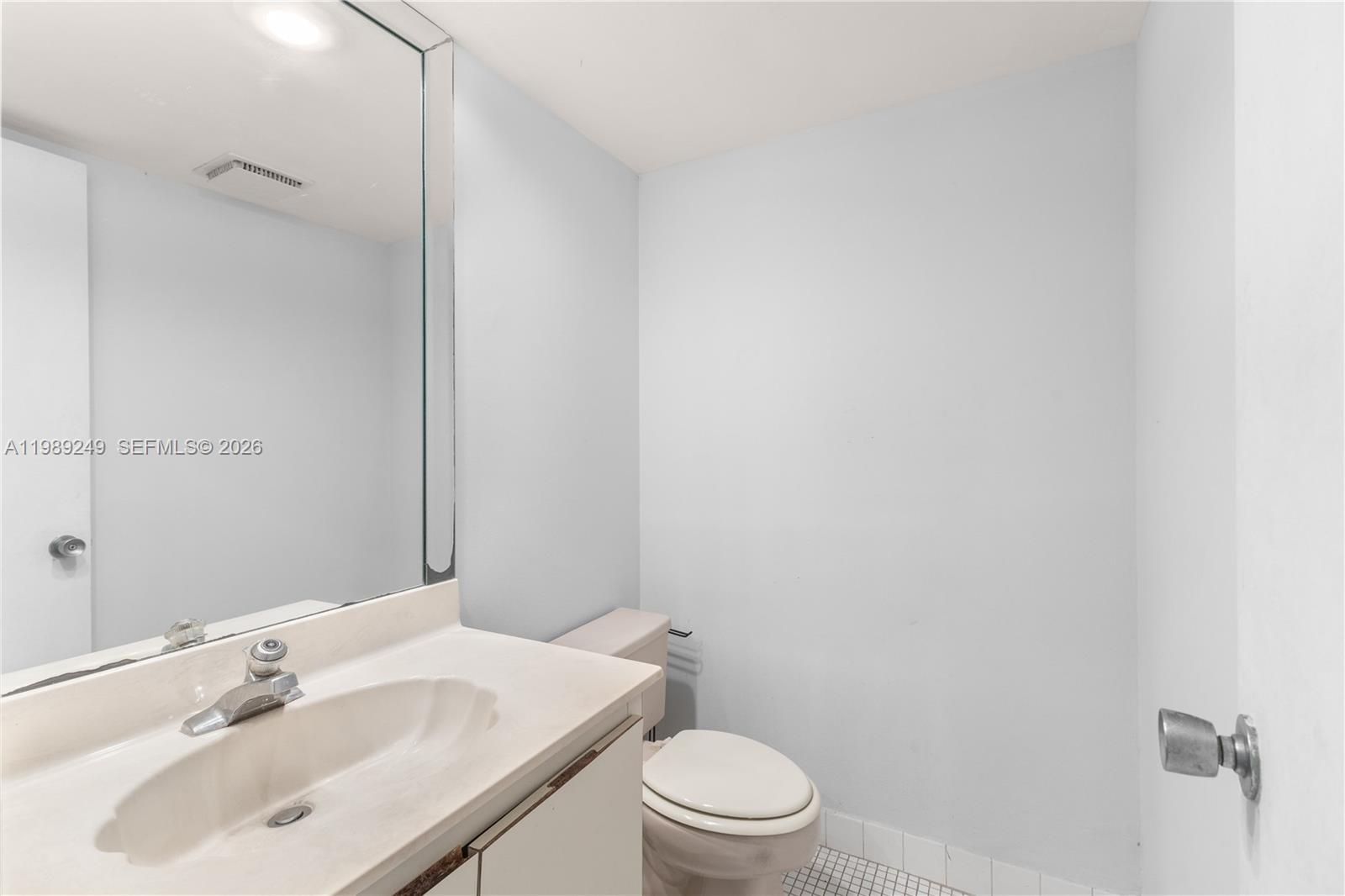 A bathroom features a white vanity with a sink, a toilet, and a large mirror — 806 Cypress Grove Ln # 111, Pompano Beach FL 33069, POMPANO BEACH, FL