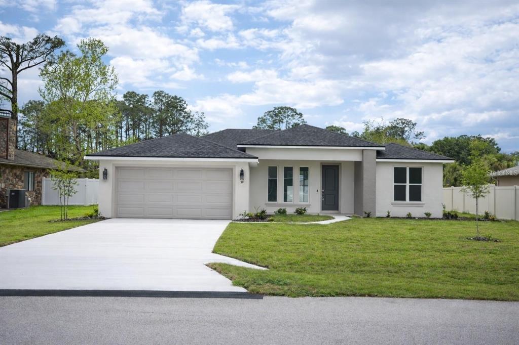 A single-story house with a two-car garage, light-colored stucco exterior, and a dark shingled roof — 15 BUD SHIRE LANE, PALM COAST, FL