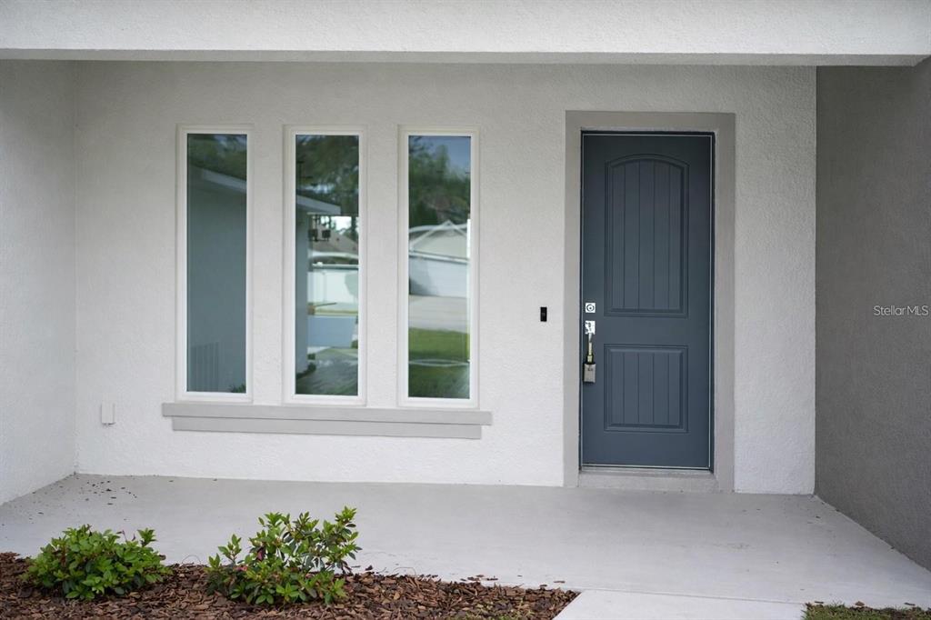 A front entrance features a dark blue door and three vertical windows on a white wall — 15 BUD SHIRE LANE, PALM COAST, FL
