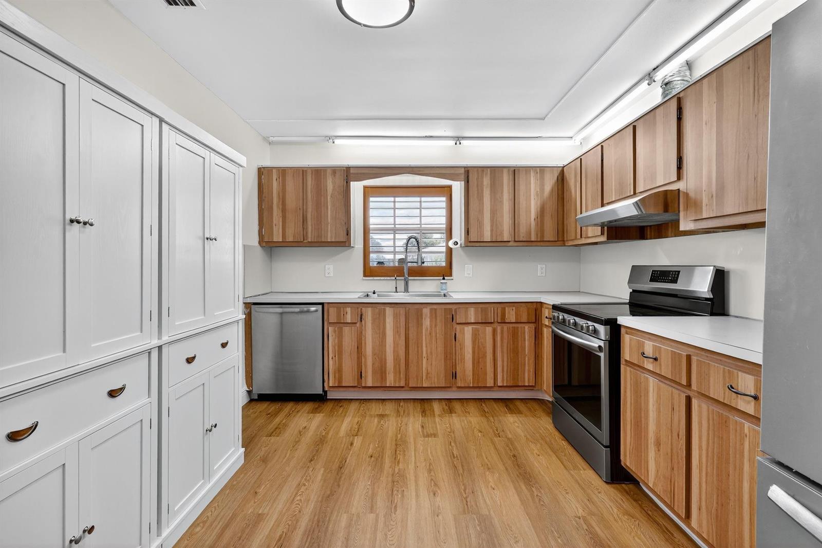A kitchen features wood cabinets, white countertops, stainless steel appliances, and a white pantry cabinet — 448 Franconia Circle # B, Lake Worth FL 33467, LAKE WORTH, FL