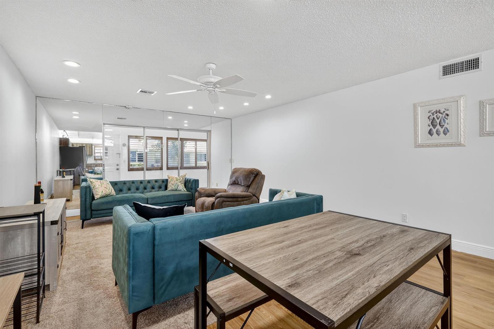 A living room features teal sofas, a brown recliner, mirrored walls, and a dining table — 448 Franconia Circle # B, Lake Worth FL 33467, LAKE WORTH, FL