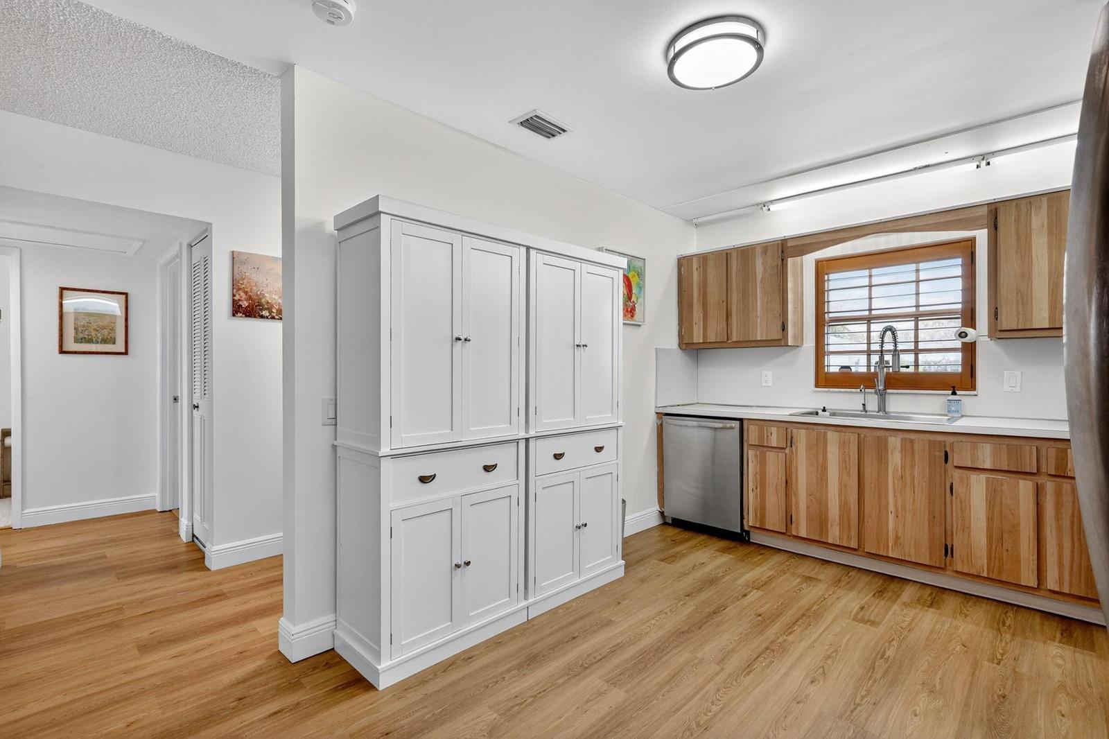 A kitchen features light wood cabinets, a white storage unit, and light-colored wood flooring — 448 Franconia Circle # B, Lake Worth FL 33467, LAKE WORTH, FL