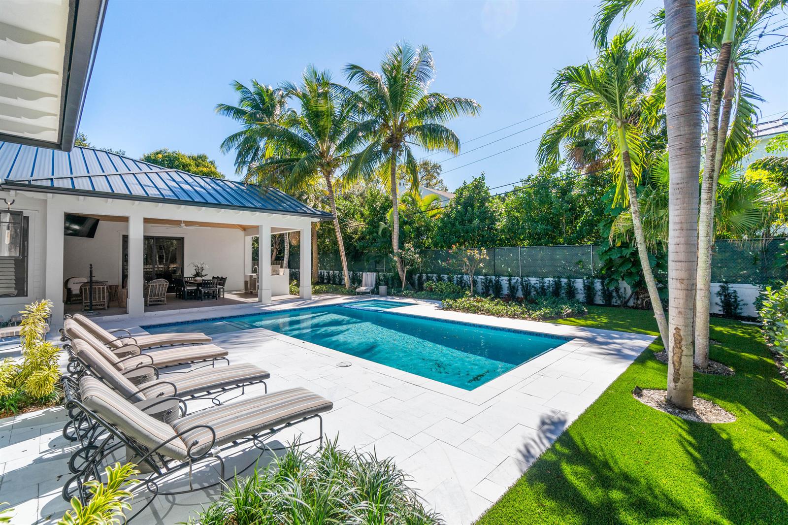 A backyard features a swimming pool, lounge chairs, a covered patio, and palm trees — 18 NW 15th Street, Delray Beach FL 33444, DELRAY BEACH, FL