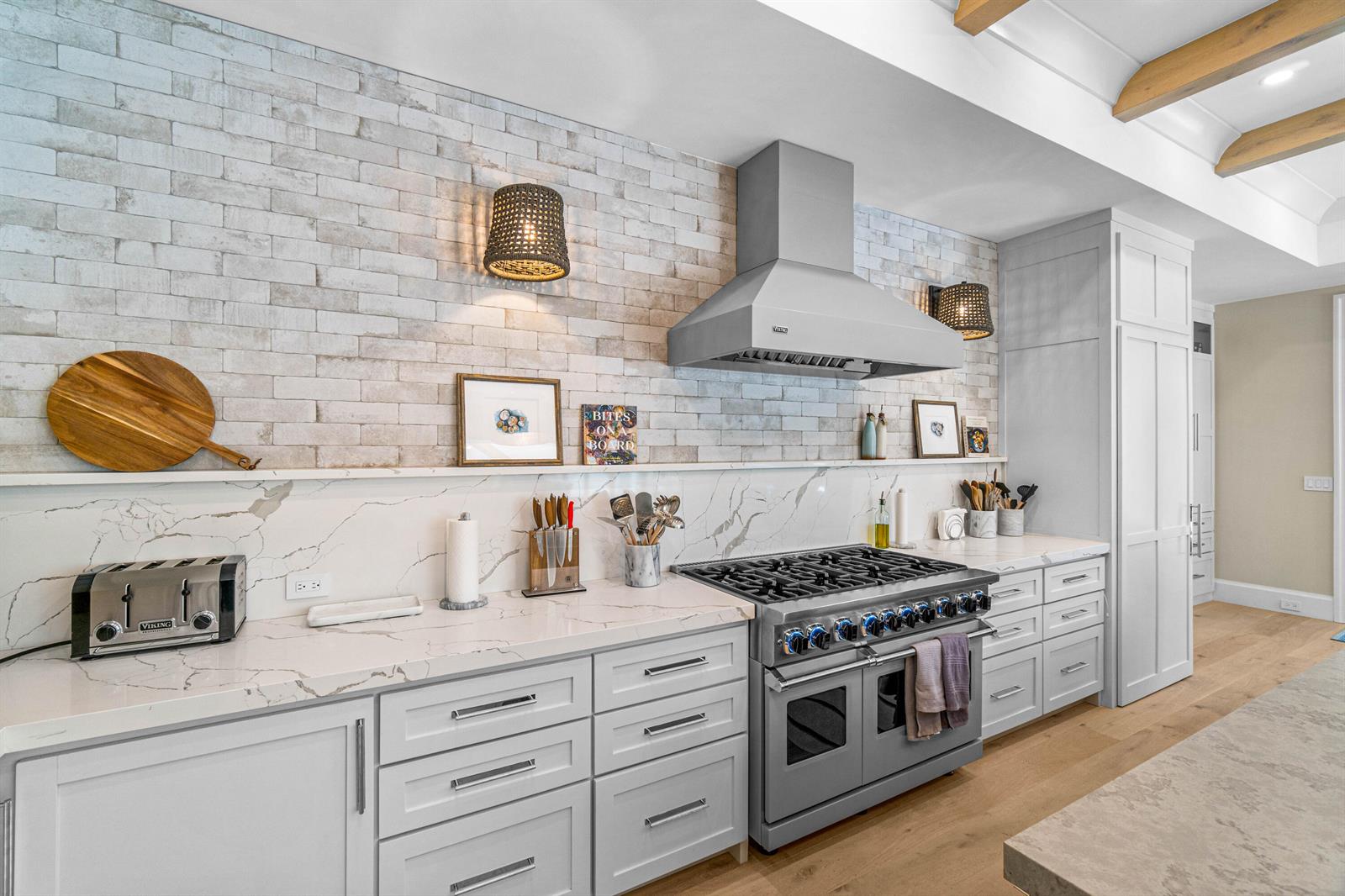 A kitchen features white cabinets, marble countertops, a brick backsplash, and a stainless steel range — 18 NW 15th Street, Delray Beach FL 33444, DELRAY BEACH, FL