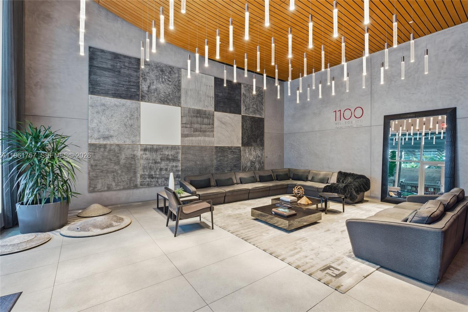 A modern lobby features a large sectional sofa, geometric wall art, and numerous hanging pendant lights — 1100 S Miami Ave # 1602, Miami FL 33130, MIAMI, FL