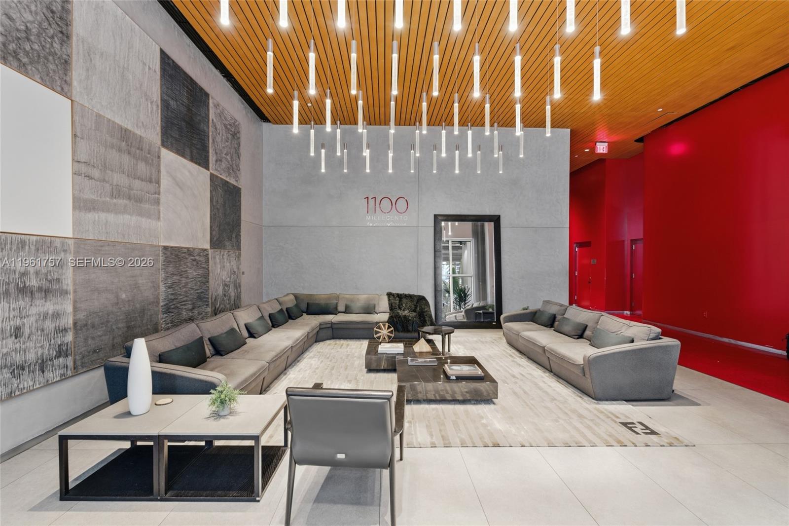 A modern lobby features gray sectional sofas, a wood-slat ceiling, and a prominent light installation — 1100 S Miami Ave # 1602, Miami FL 33130, MIAMI, FL