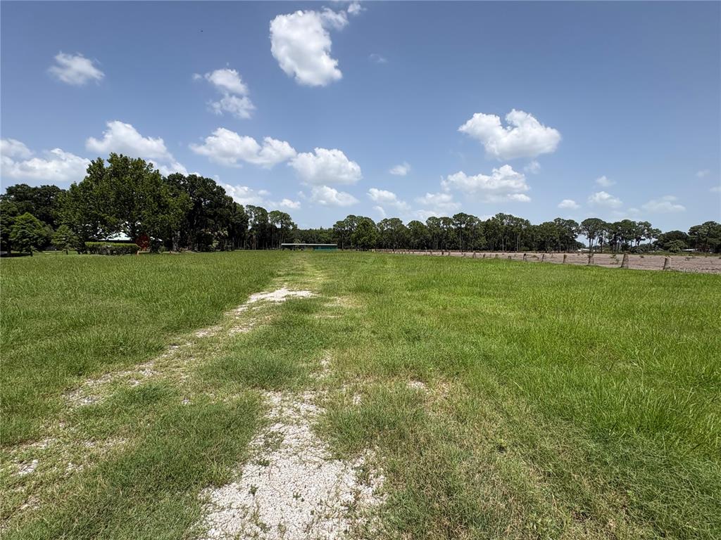 A wide, grassy field features a gravel path leading toward a distant green structure — 0 HAMILTON ROAD, LAKELAND, FL
