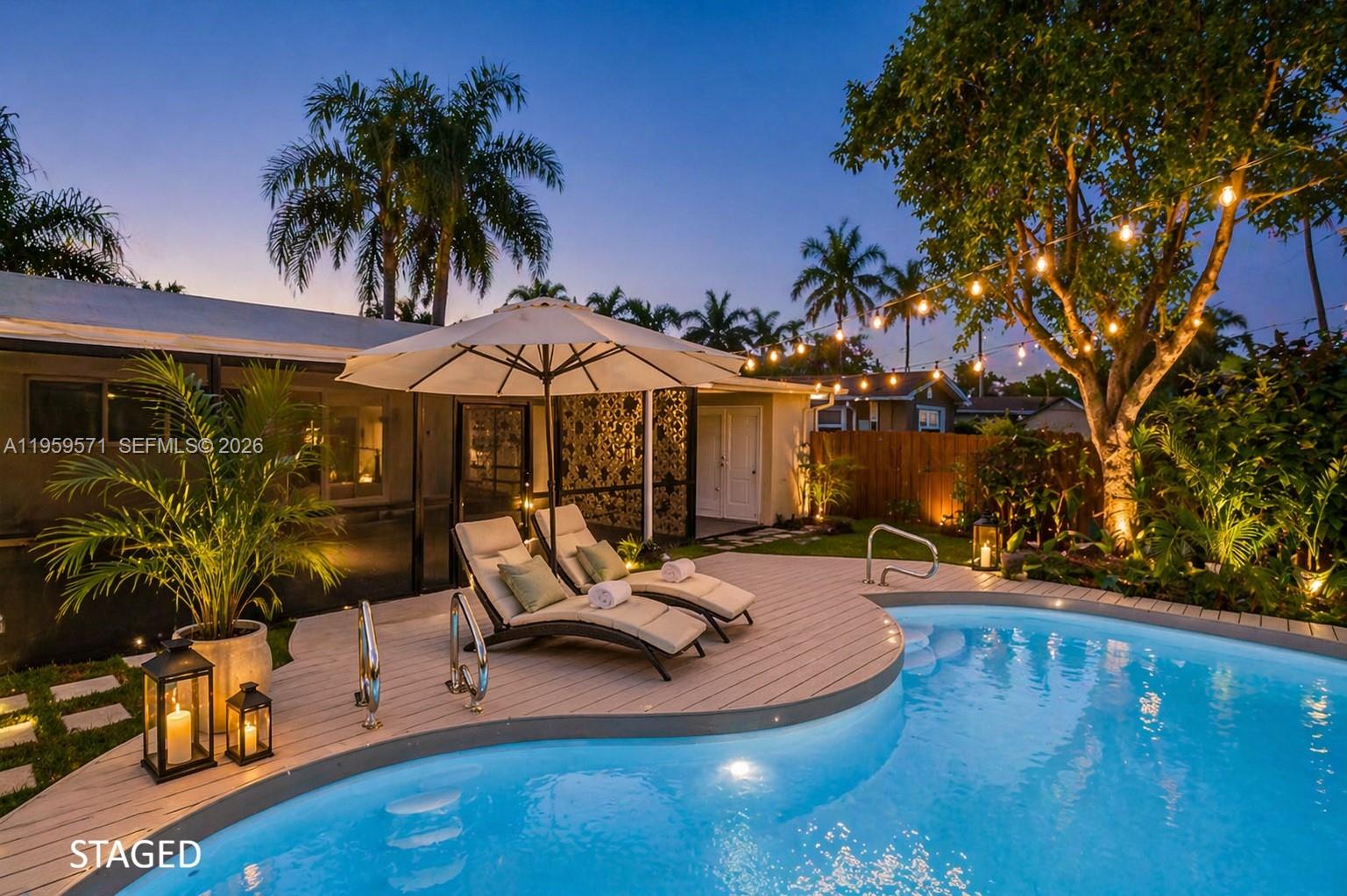 A backyard pool area features a wooden deck with lounge chairs under an umbrella — 1507 Harding St, Hollywood FL 33020, HOLLYWOOD, FL