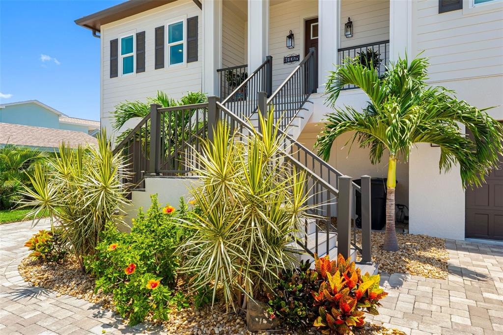 A house exterior features a raised front porch with stairs, landscaping, and a paved driveway — 16025 REDINGTON DRIVE, REDINGTON BEACH, FL