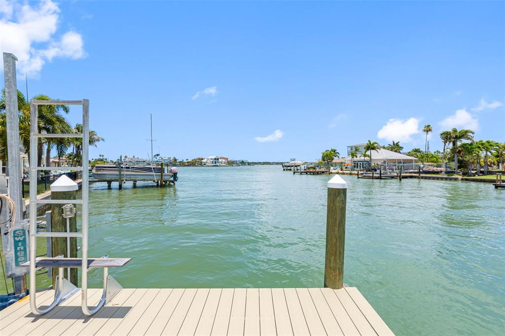 A wooden dock overlooks a canal with boats and waterfront homes under a blue sky — 16025 REDINGTON DRIVE, REDINGTON BEACH, FL